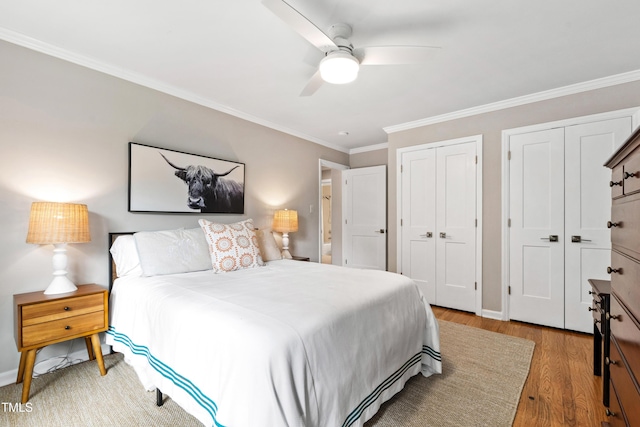 433 Rosehaven Dr, Raleigh, NC 27609 - bedroom featuring two closets, ornamental molding, wood finished floors, and a ceiling fan