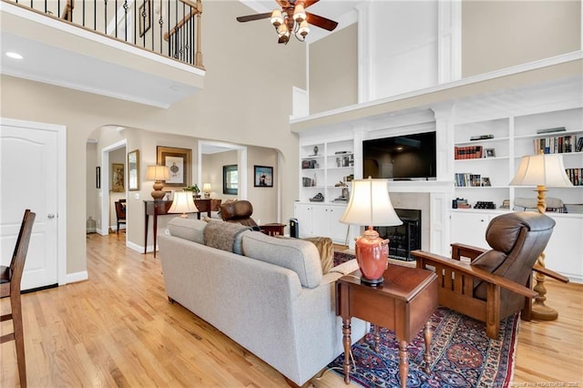 6558 Countryside Dr, Fayetteville, NC 28311 - living room with arched walkways, a ceiling fan, wood finished floors, a towering ceiling, and a fireplace