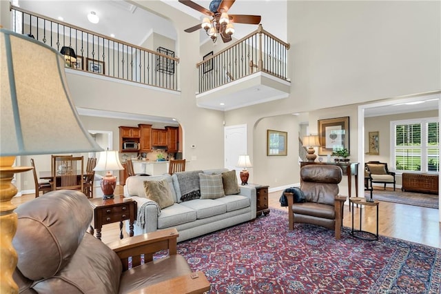6558 Countryside Dr, Fayetteville, NC 28311 - living area with ceiling fan, arched walkways, a high ceiling, wood finished floors, and baseboards
