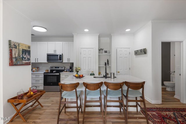 800 Savannah Ridge Rd Unit 109, Holly Springs, NC 27540 - kitchen featuring stainless steel appliances, light wood-style flooring, crown molding, a breakfast bar area, and light countertops