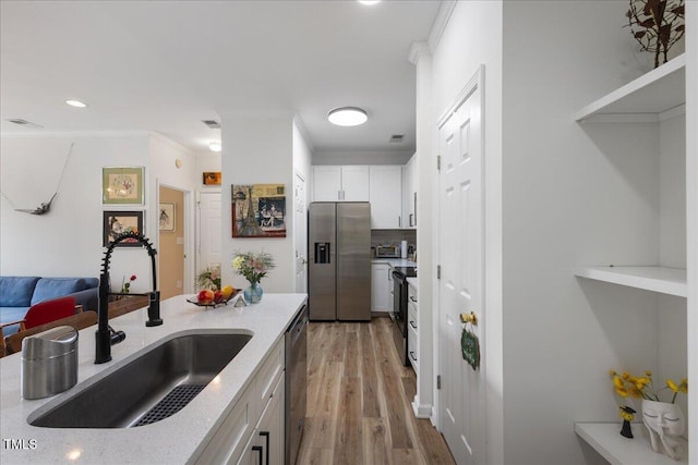 800 Savannah Ridge Rd Unit 109, Holly Springs, NC 27540 - kitchen with appliances with stainless steel finishes, ornamental molding, light stone counters, white cabinetry, and light wood-type flooring