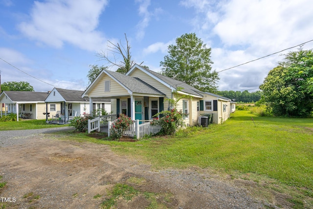 306 W Main St, Pine Level, NC 27568 - view of front facade featuring a porch, dirt driveway, a front yard, a shingled roof, and central AC unit