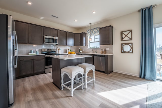 303 Enfield Dr, Carthage, NC 28327 - kitchen featuring appliances with stainless steel finishes, dark brown cabinetry, tasteful backsplash, light countertops, and a breakfast bar area