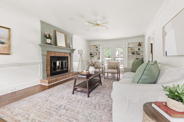 16 Cedar Hill Dr, Durham, NC 27713 - living room featuring built in shelves, crown molding, french doors, a brick fireplace, and wood finished floors