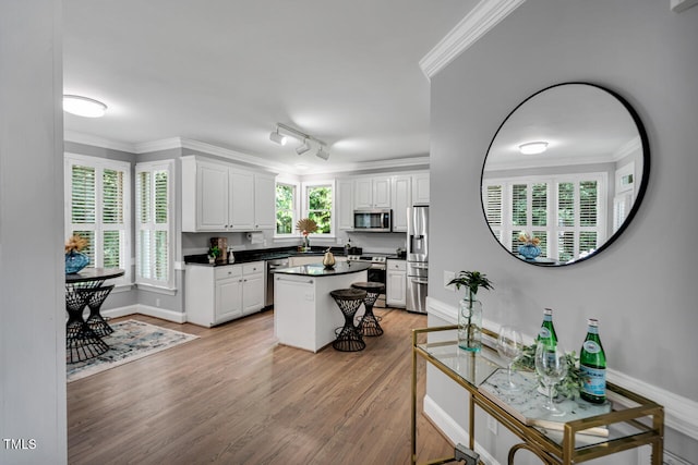 12 Gatesway Ct, Durham, NC 27707 - kitchen featuring appliances with stainless steel finishes, light wood-style floors, white cabinetry, dark countertops, and ornamental molding
