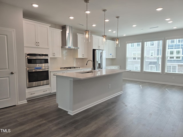 2203 Lambert Rd Unit 67, Cary, NC 27519 - kitchen featuring wall chimney range hood, appliances with stainless steel finishes, a kitchen island with sink, dark wood-style flooring, and recessed lighting