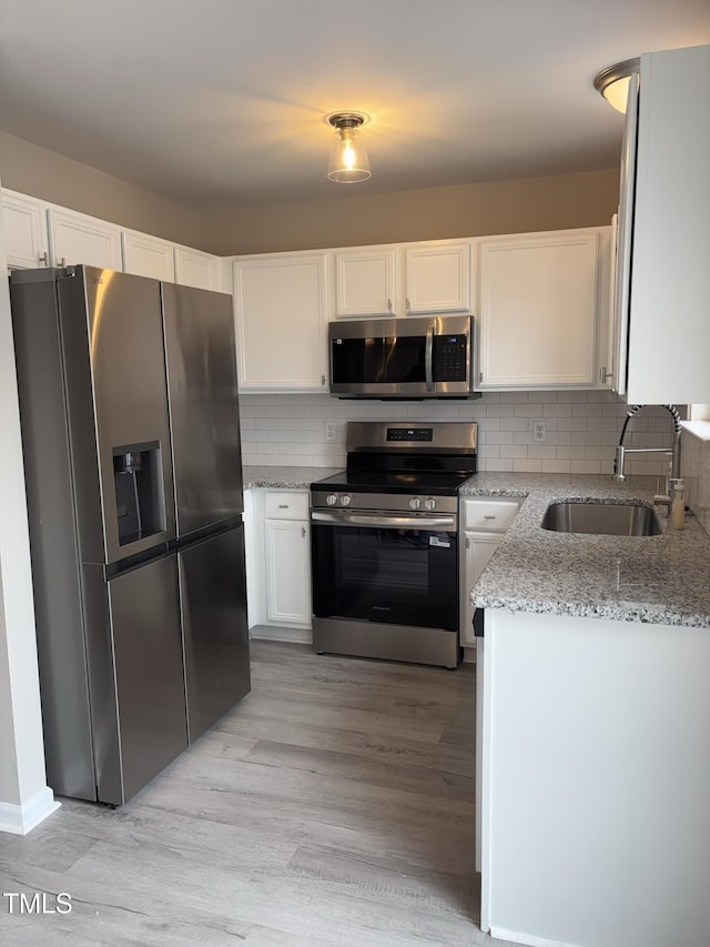 7710 River Field Dr, Raleigh, NC 27616 - kitchen with appliances with stainless steel finishes, a sink, light stone counters, white cabinetry, and light wood finished floors