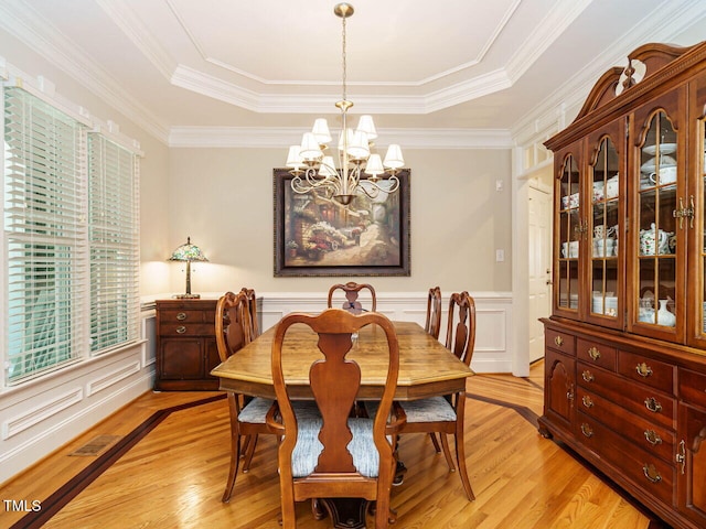 8504 Carlton Oaks Dr, Wake Forest, NC 27587 - dining area featuring a chandelier, light wood-type flooring, a raised ceiling, a decorative wall, and wainscoting