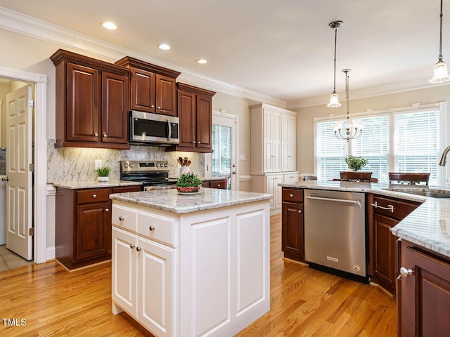 8504 Carlton Oaks Dr, Wake Forest, NC 27587 - kitchen featuring appliances with stainless steel finishes, light wood-style flooring, ornamental molding, hanging light fixtures, and plenty of natural light
