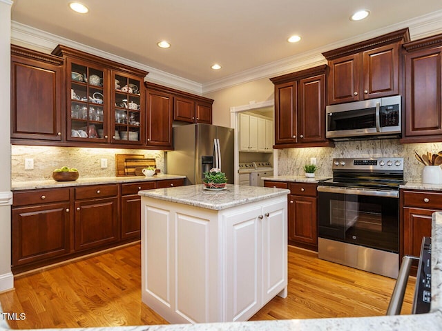 8504 Carlton Oaks Dr, Wake Forest, NC 27587 - kitchen with appliances with stainless steel finishes, washing machine and clothes dryer, crown molding, light wood-style floors, and backsplash