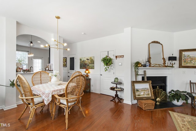 818 Bryant St, Raleigh, NC 27603 - dining area with wood finished floors, a chandelier, a fireplace with flush hearth, and arched walkways