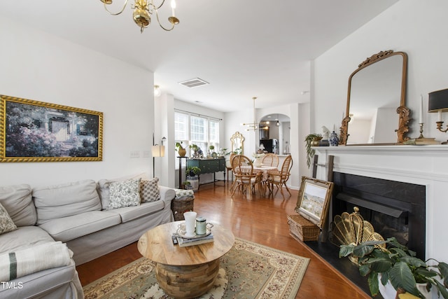 818 Bryant St, Raleigh, NC 27603 - living room with a chandelier, wood finished floors, a fireplace with raised hearth, and arched walkways