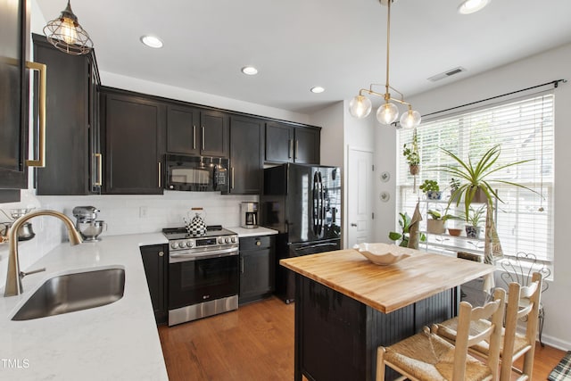 818 Bryant St, Raleigh, NC 27603 - kitchen featuring black appliances, wood counters, wood finished floors, decorative backsplash, and recessed lighting