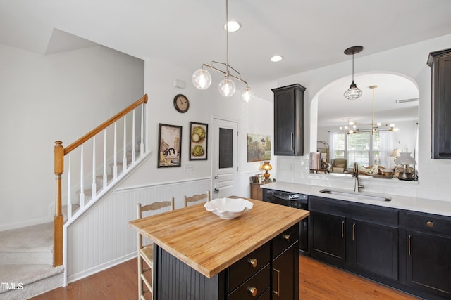 818 Bryant St, Raleigh, NC 27603 - kitchen featuring wood counters, light wood-style flooring, hanging light fixtures, arched walkways, and a wainscoted wall