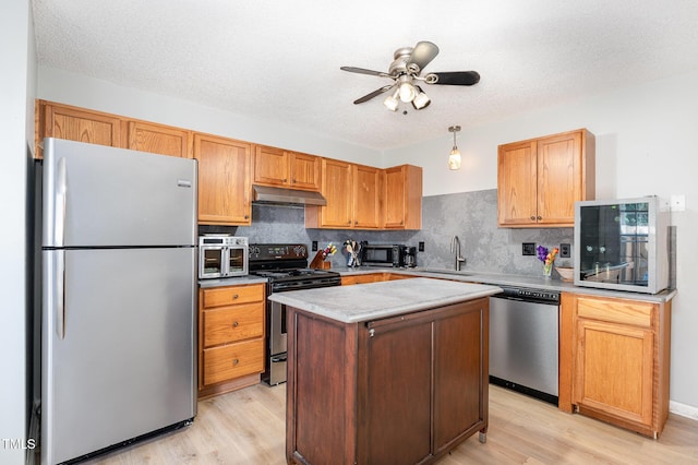 2600 Dwight Pl, Raleigh, NC 27610 - kitchen with stainless steel appliances, under cabinet range hood, light wood finished floors, decorative backsplash, and a textured ceiling