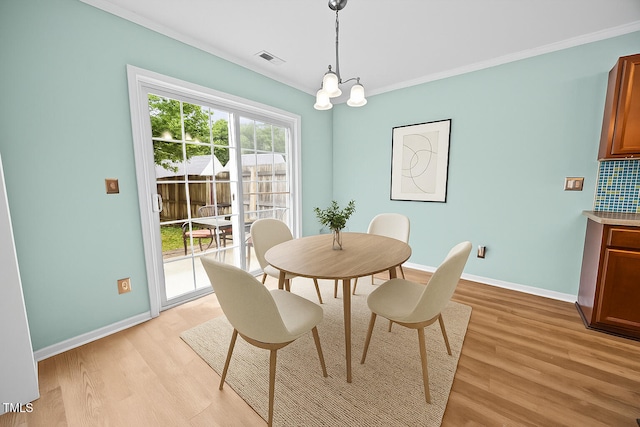 5561 Roan Mountain Pl, Raleigh, NC 27613 - dining space with light wood-type flooring, ornamental molding, and a chandelier