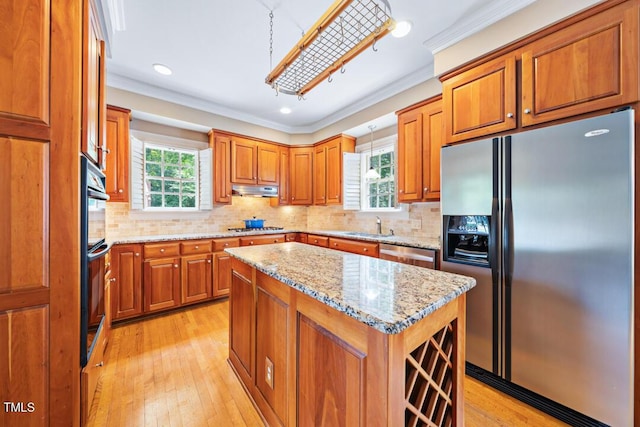 305 Lochridge Dr, Roxboro, NC 27573 - kitchen featuring appliances with stainless steel finishes, brown cabinets, ornamental molding, a kitchen island, and light wood-style floors