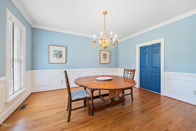 305 Lochridge Dr, Roxboro, NC 27573 - dining room featuring a chandelier, ornamental molding, light wood finished floors, wainscoting, and a decorative wall