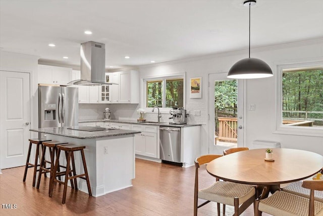 6609 Hunters Ln, Durham, NC 27713 - kitchen with island range hood, appliances with stainless steel finishes, decorative backsplash, a kitchen island, and wood finished floors