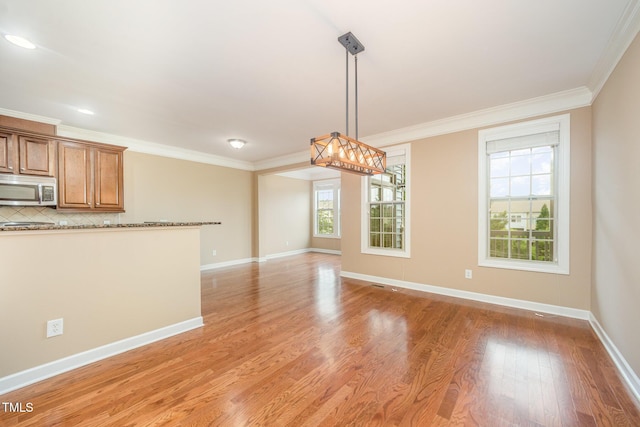 404 Panorama Park Pl, Cary, NC 27519 - kitchen featuring stainless steel microwave, brown cabinets, light wood-type flooring, crown molding, and hanging light fixtures