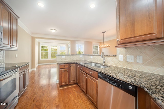 404 Panorama Park Pl, Cary, NC 27519 - kitchen with stainless steel appliances, ornamental molding, light wood-style floors, a peninsula, and dark stone countertops