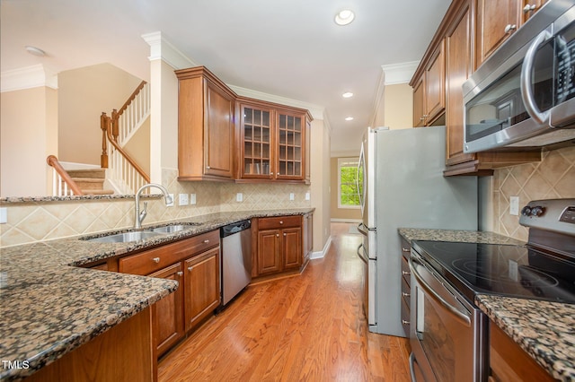 404 Panorama Park Pl, Cary, NC 27519 - kitchen with stainless steel appliances, ornamental molding, brown cabinetry, light wood finished floors, and dark stone countertops