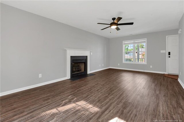 9031 Grouse Run Ln, Fayetteville, NC 28314 - unfurnished living room featuring dark wood-style flooring, a fireplace with flush hearth, ceiling fan, and baseboards