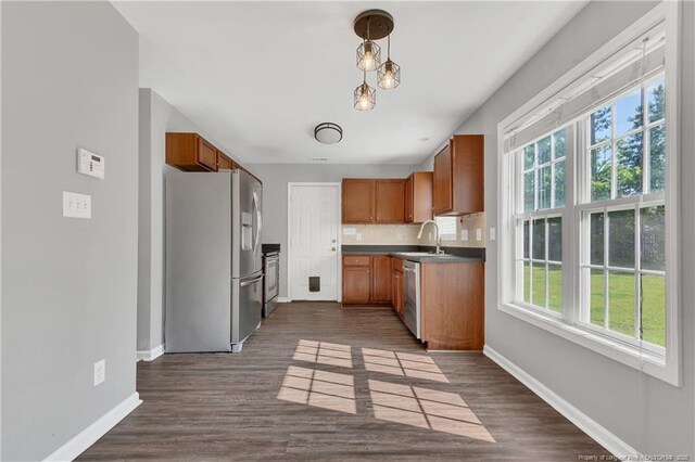 9031 Grouse Run Ln, Fayetteville, NC 28314 - kitchen featuring appliances with stainless steel finishes, baseboards, brown cabinetry, a sink, and tasteful backsplash