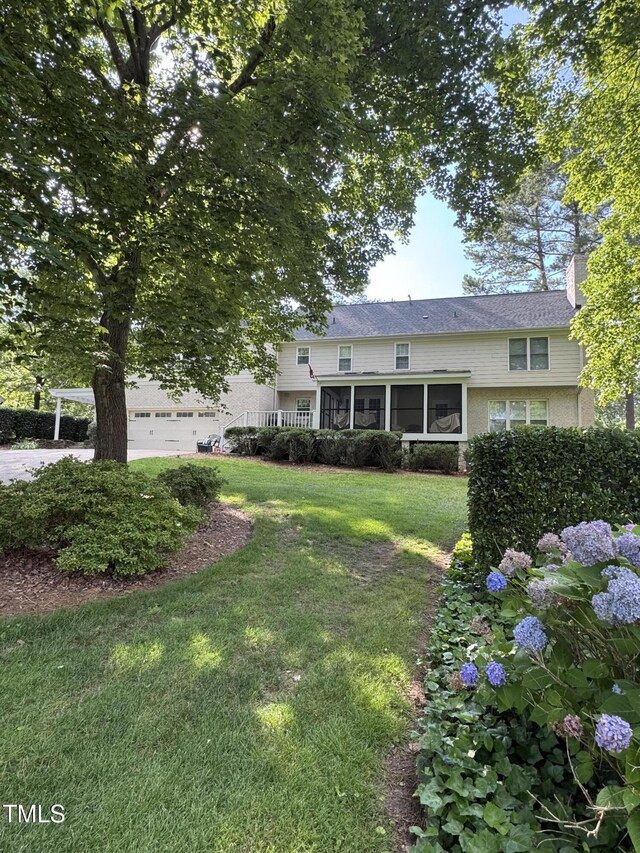 7140 N Ridge Dr, Raleigh, NC 27615 - view of front facade featuring a sunroom, a front lawn, a chimney, and a garage