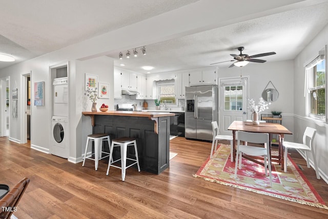 2322 Stroller Ave, Durham, NC 27705 - kitchen featuring stainless steel fridge with ice dispenser, stacked washer / dryer, light wood finished floors, and a textured ceiling