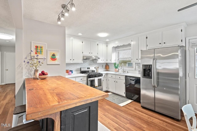 2322 Stroller Ave, Durham, NC 27705 - kitchen featuring stainless steel appliances, under cabinet range hood, a textured ceiling, a peninsula, and white cabinetry
