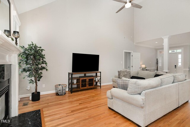 6313 Belle Crest Dr, Raleigh, NC 27612 - living room featuring a high end fireplace, high vaulted ceiling, ceiling fan, light wood-style flooring, and decorative columns