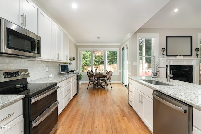 6313 Belle Crest Dr, Raleigh, NC 27612 - kitchen featuring appliances with stainless steel finishes, light wood-style floors, white cabinetry, ornamental molding, and backsplash