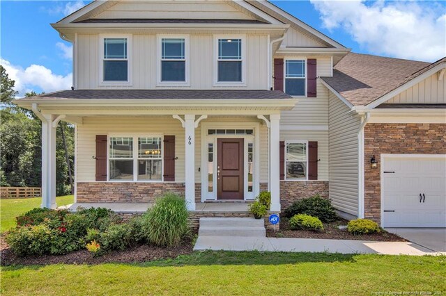 66 S Hawks Ridge Ln, Smithfield, NC 27577 - craftsman-style home featuring stone siding, a porch, board and batten siding, an attached garage, and a front lawn