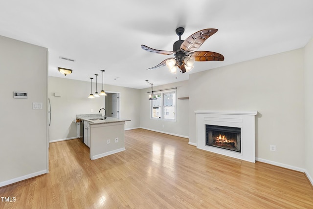 3427 Mill Run, Raleigh, NC 27612 - unfurnished living room with a ceiling fan, a lit fireplace, light wood-type flooring, a sink, and baseboards