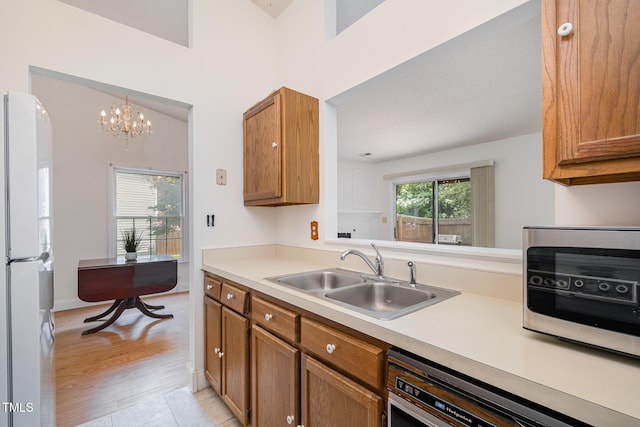 2213 Alpine Rd, Durham, NC 27707 - kitchen featuring freestanding refrigerator, brown cabinetry, dishwasher, light countertops, and a chandelier