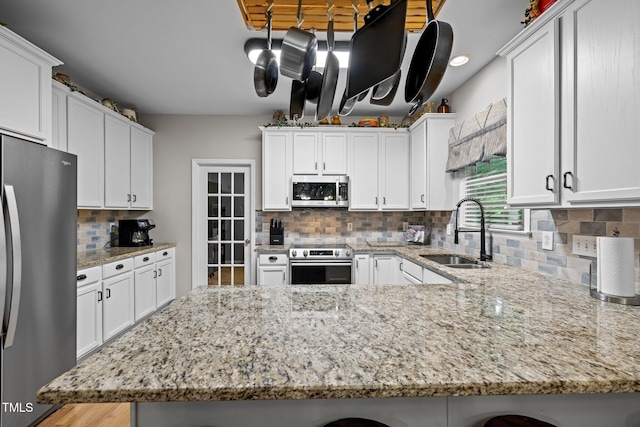 15 Smoketree Ct, Durham, NC 27712 - kitchen with stainless steel appliances, white cabinets, a peninsula, and tasteful backsplash