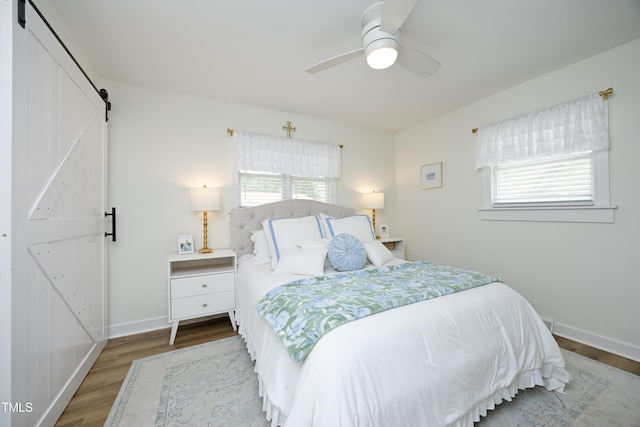 2320 Marks Creek Rd, Knightdale, NC 27545 - bedroom with a barn door, wood finished floors, and a ceiling fan