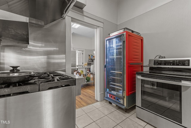 309 W Divine St, Dunn, NC 28334 - kitchen featuring stainless steel electric range oven, light tile patterned flooring, range hood, and beverage cooler