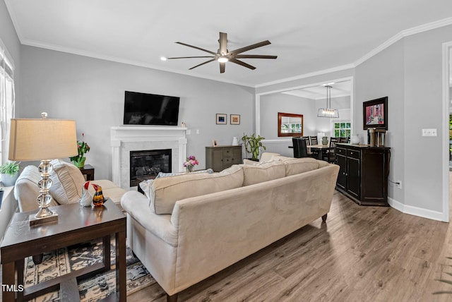 200 Holly Branch Dr, Holly Springs, NC 27540 - living area featuring healthy amount of natural light, wood finished floors, a fireplace, a ceiling fan, and crown molding