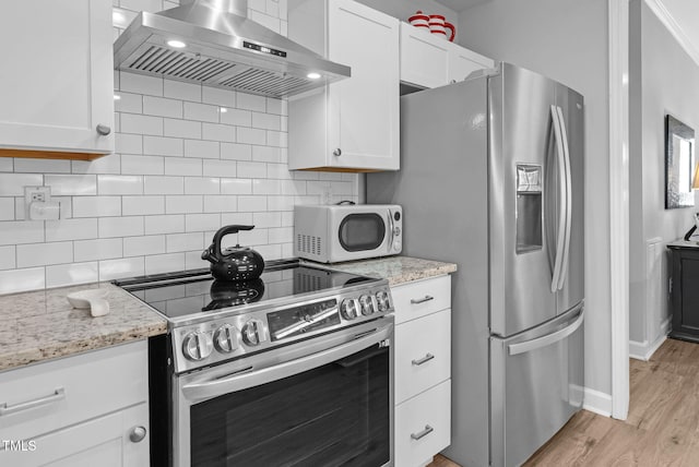 200 Holly Branch Dr, Holly Springs, NC 27540 - kitchen featuring appliances with stainless steel finishes, wall chimney exhaust hood, white cabinetry, and light wood-style floors
