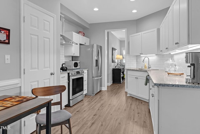 200 Holly Branch Dr, Holly Springs, NC 27540 - kitchen featuring appliances with stainless steel finishes, backsplash, white cabinets, light wood-style flooring, and recessed lighting