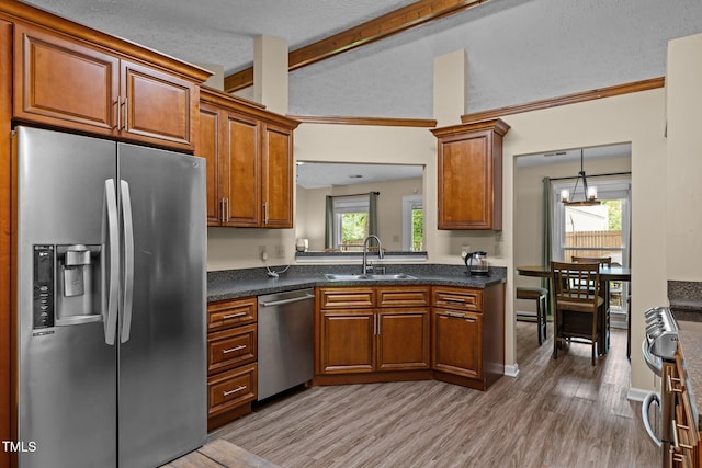 5801 Hadrian Dr, Durham, NC 27703 - kitchen with stainless steel appliances, brown cabinets, dark countertops, light wood finished floors, and a chandelier