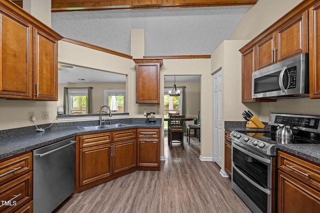 5801 Hadrian Dr, Durham, NC 27703 - kitchen with appliances with stainless steel finishes, wood finished floors, dark countertops, and brown cabinets