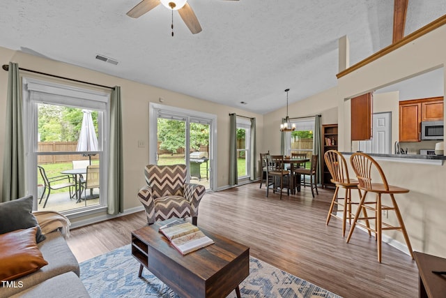 5801 Hadrian Dr, Durham, NC 27703 - living area featuring a textured ceiling, vaulted ceiling, a chandelier, light wood finished floors, and ceiling fan