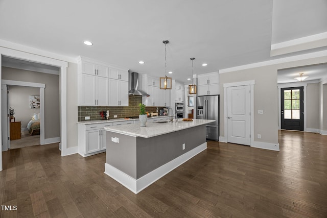 7410 Chouder Ln, Wake Forest, NC 27587 - kitchen featuring high end fridge, wall chimney exhaust hood, white cabinets, a kitchen island with sink, and recessed lighting