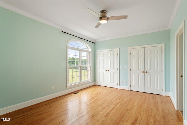 8415 Meadow View Ln, Bahama, NC 27503 - unfurnished bedroom with crown molding, multiple closets, light wood finished floors, and ceiling fan