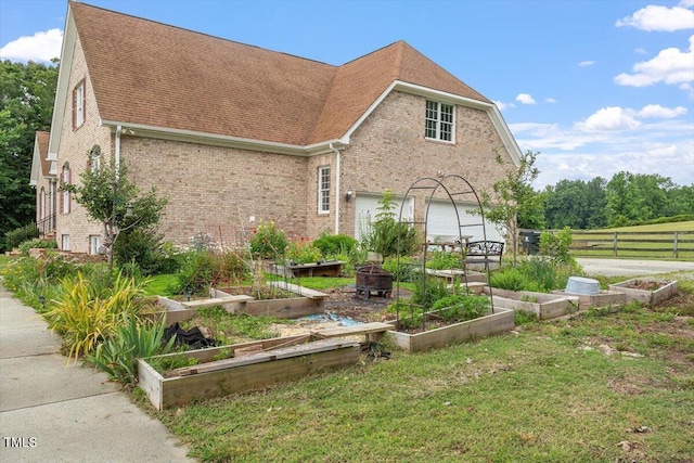 8415 Meadow View Ln, Bahama, NC 27503 - view of front of property featuring a vegetable garden, brick siding, roof with shingles, and an attached garage
