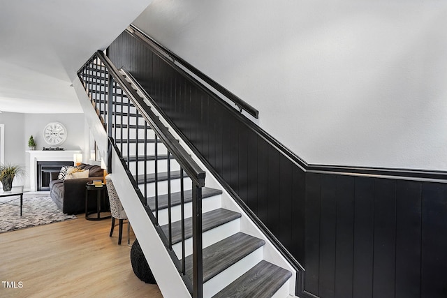 7708 Falcon Rest Cir, Raleigh, NC 27615 - stairway featuring wood finished floors, a fireplace, and a wainscoted wall