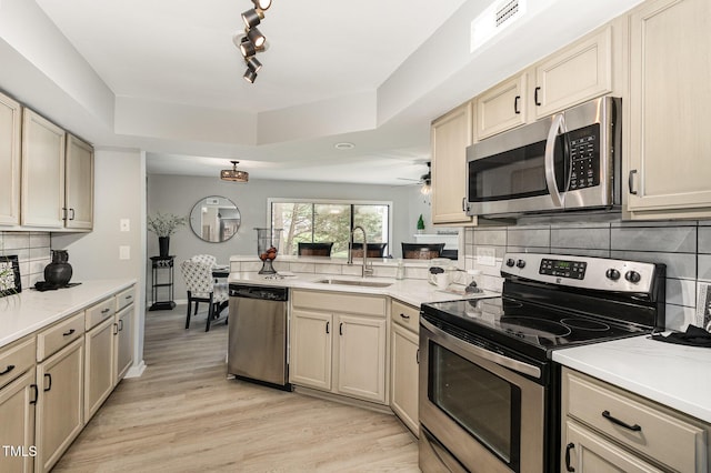 7708 Falcon Rest Cir, Raleigh, NC 27615 - kitchen with stainless steel appliances, a peninsula, a tray ceiling, light countertops, and backsplash